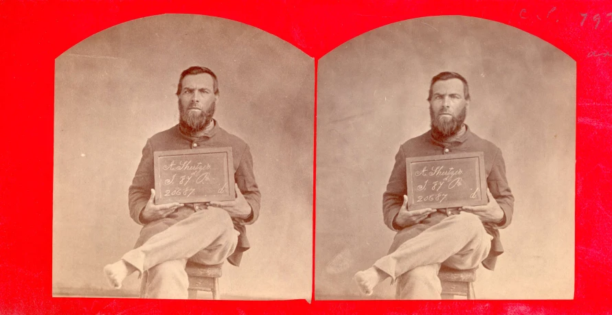 a vintage portrait showing two men with beards one holding a plaque and the other standing in a chair