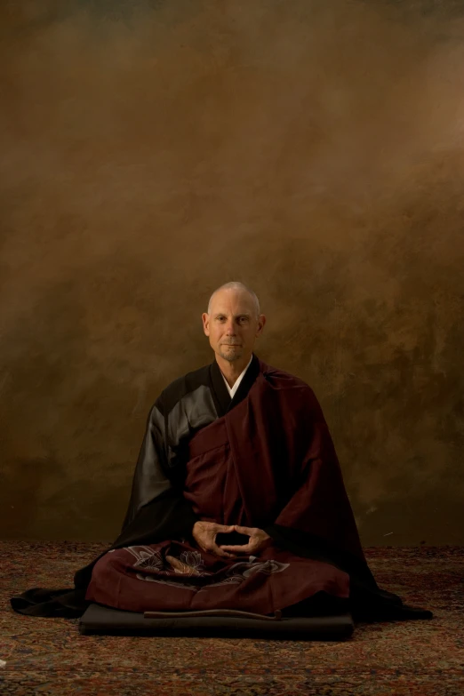 a man sitting on a blanket with a robe on