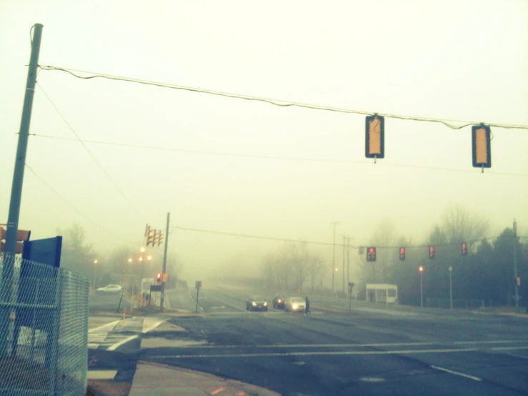 a busy intersection with red traffic lights on a foggy day