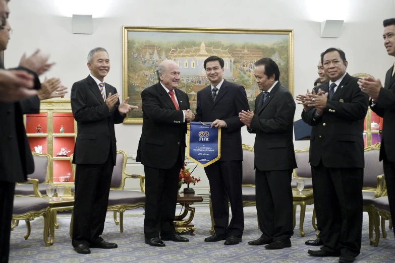 three men standing while shaking hands in front of a painting