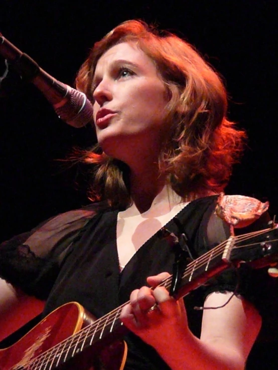 a woman that is holding a guitar in her hand