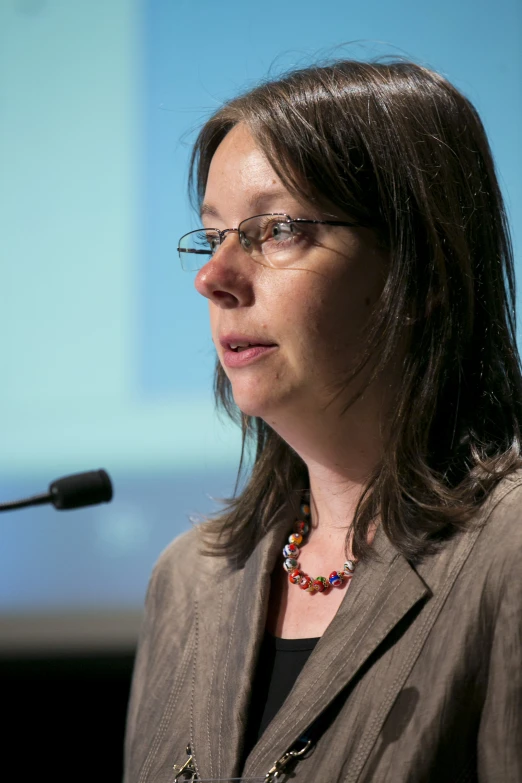 the woman in glasses is speaking at a seminar