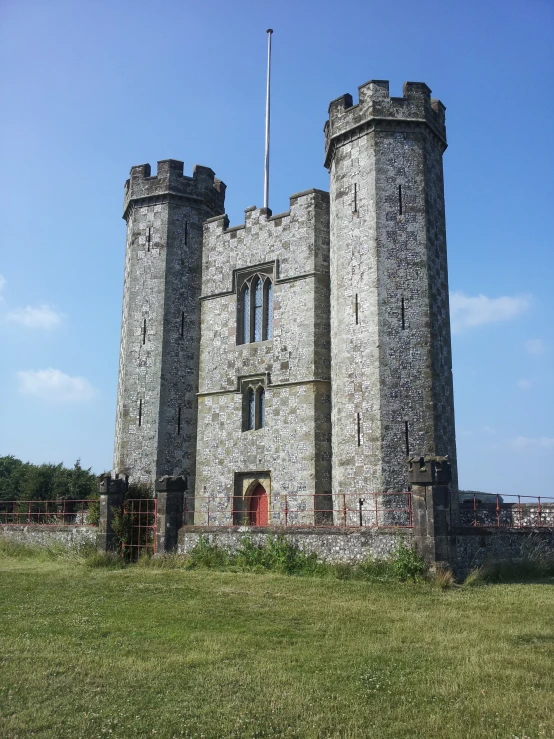 the castle is sitting in a field on a sunny day