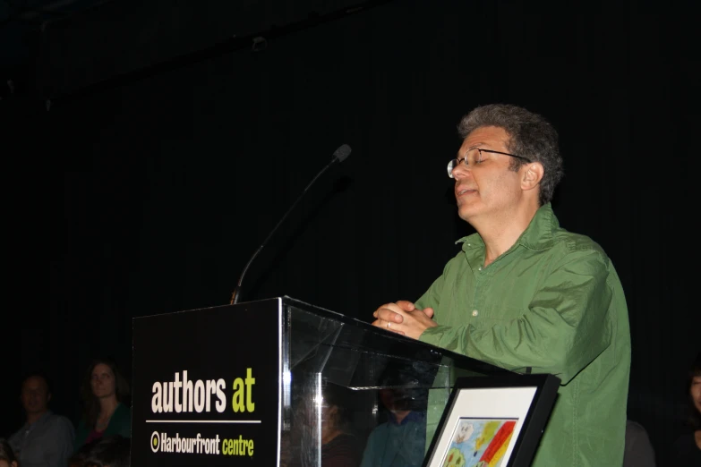 man speaking on podium with audience in background