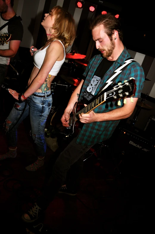 two young people are playing guitars in a black and white striped room