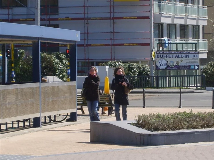 two women in jackets standing in a city square