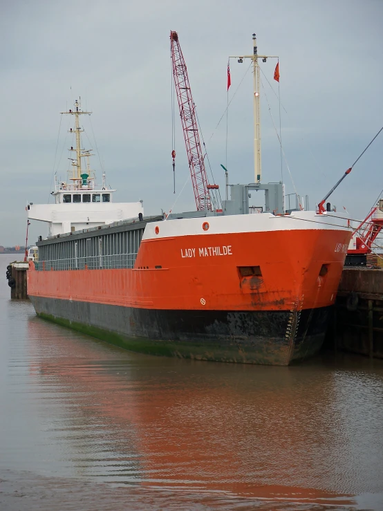 large boat at dock with craned posts in background