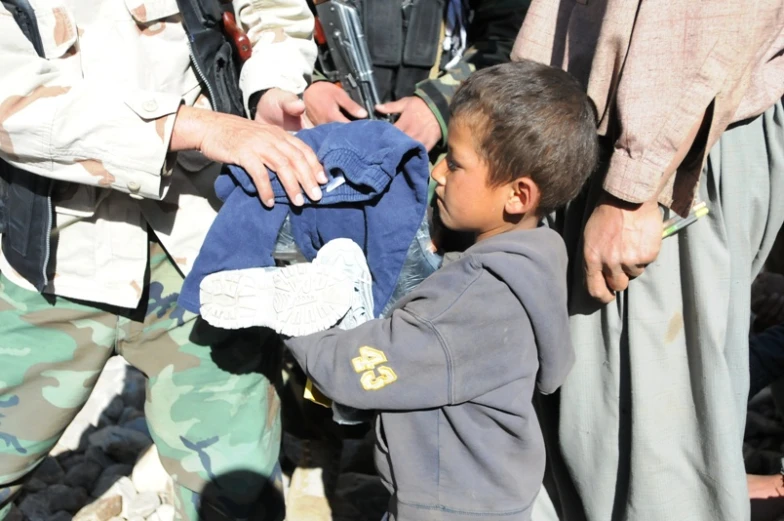 a boy being handed a shirt by some people