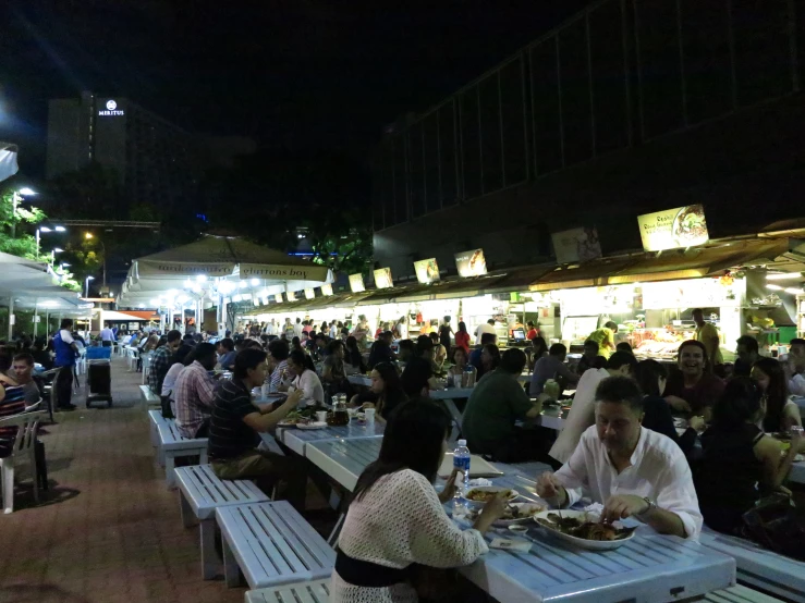 several people dining at outdoor tables outside at night