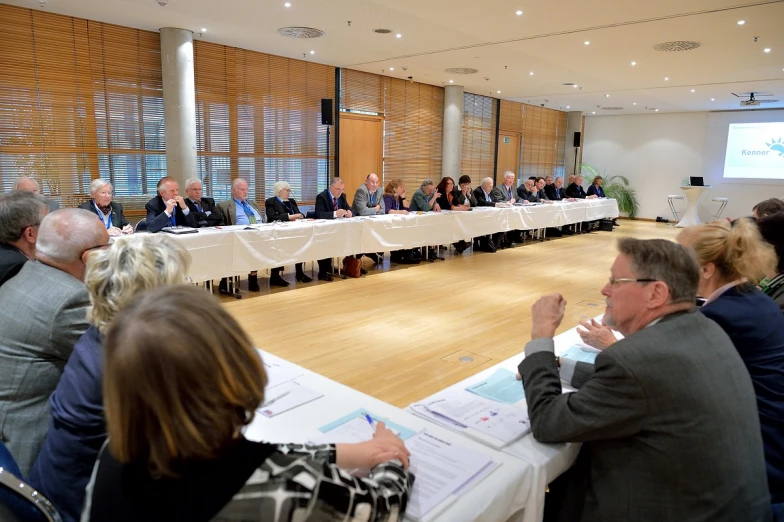 some people sitting around tables and chairs watching speakers