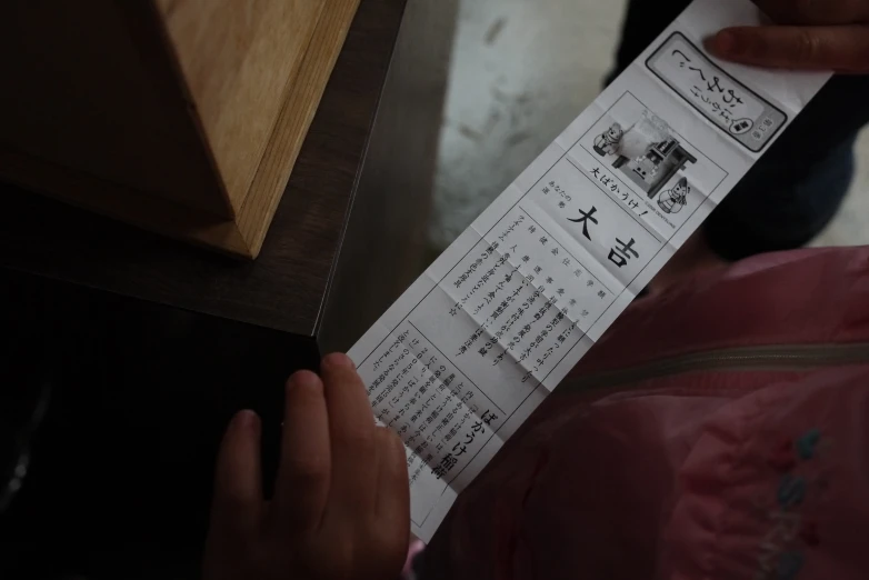 the persons hand is holding a paper with chinese writing