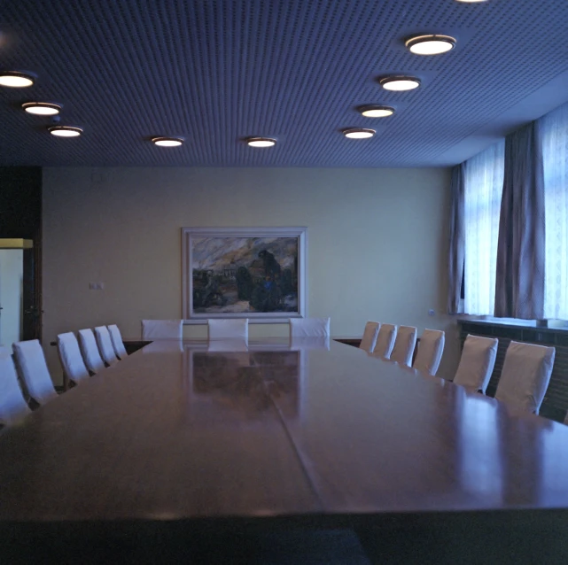 a conference room with large, square tables and white chairs