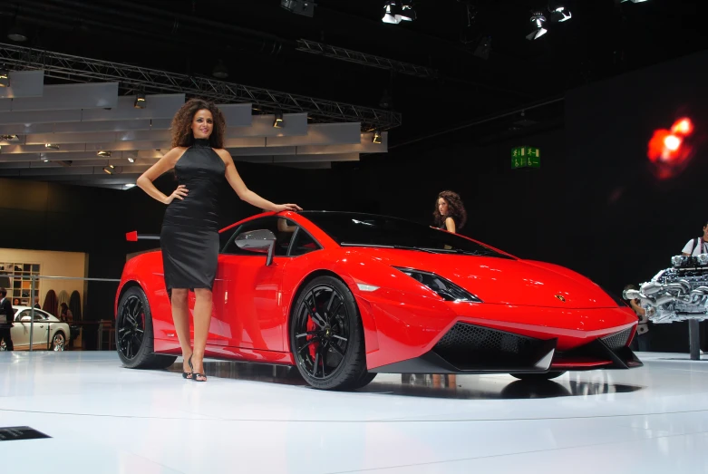 a lady is posing next to a supercar