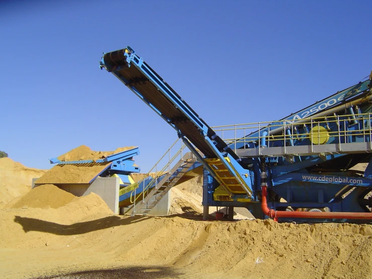 a blue machine is moving sand out onto the beach