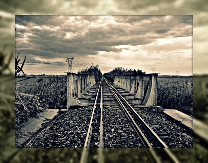 black and white image of railroad tracks going across an old bridge