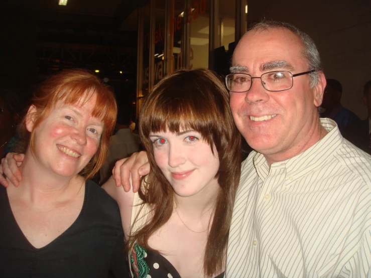 three people smiling while standing together in front of the camera