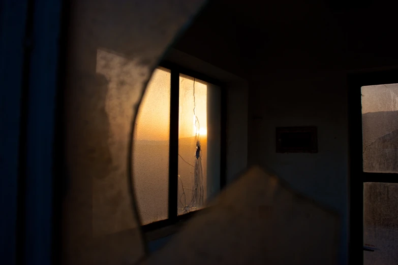 the inside view of a house through an outside window with the sun peeking in