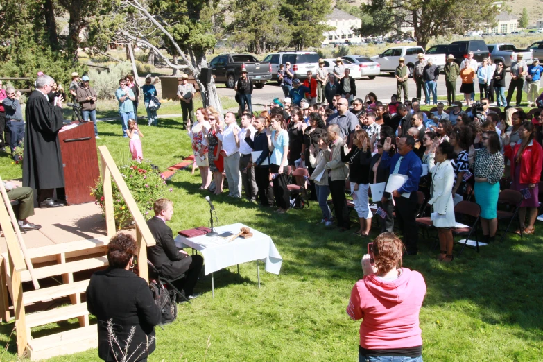 a large group of people on green grass outside a church