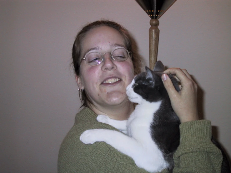 a woman holding a cat up and looking at the camera