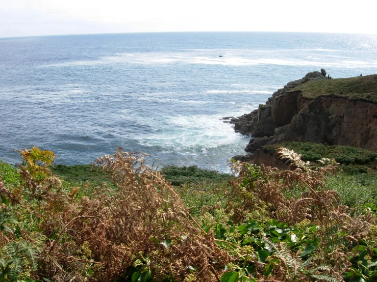 a cliff near a body of water with water in the background