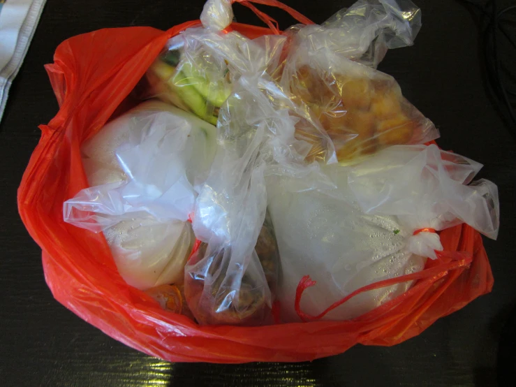 bagged fruits and vegetables sitting in a red bowl