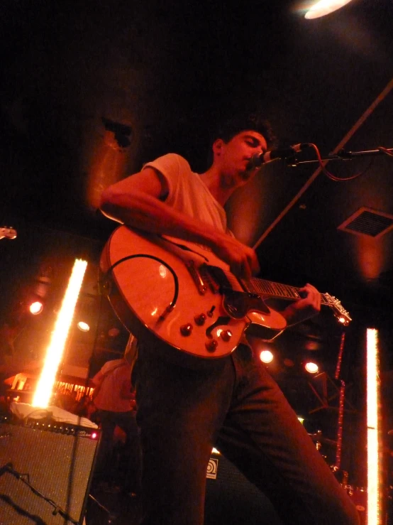 a man playing guitar on stage with his legs crossed