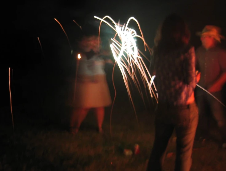 people on a grassy field with fire wands