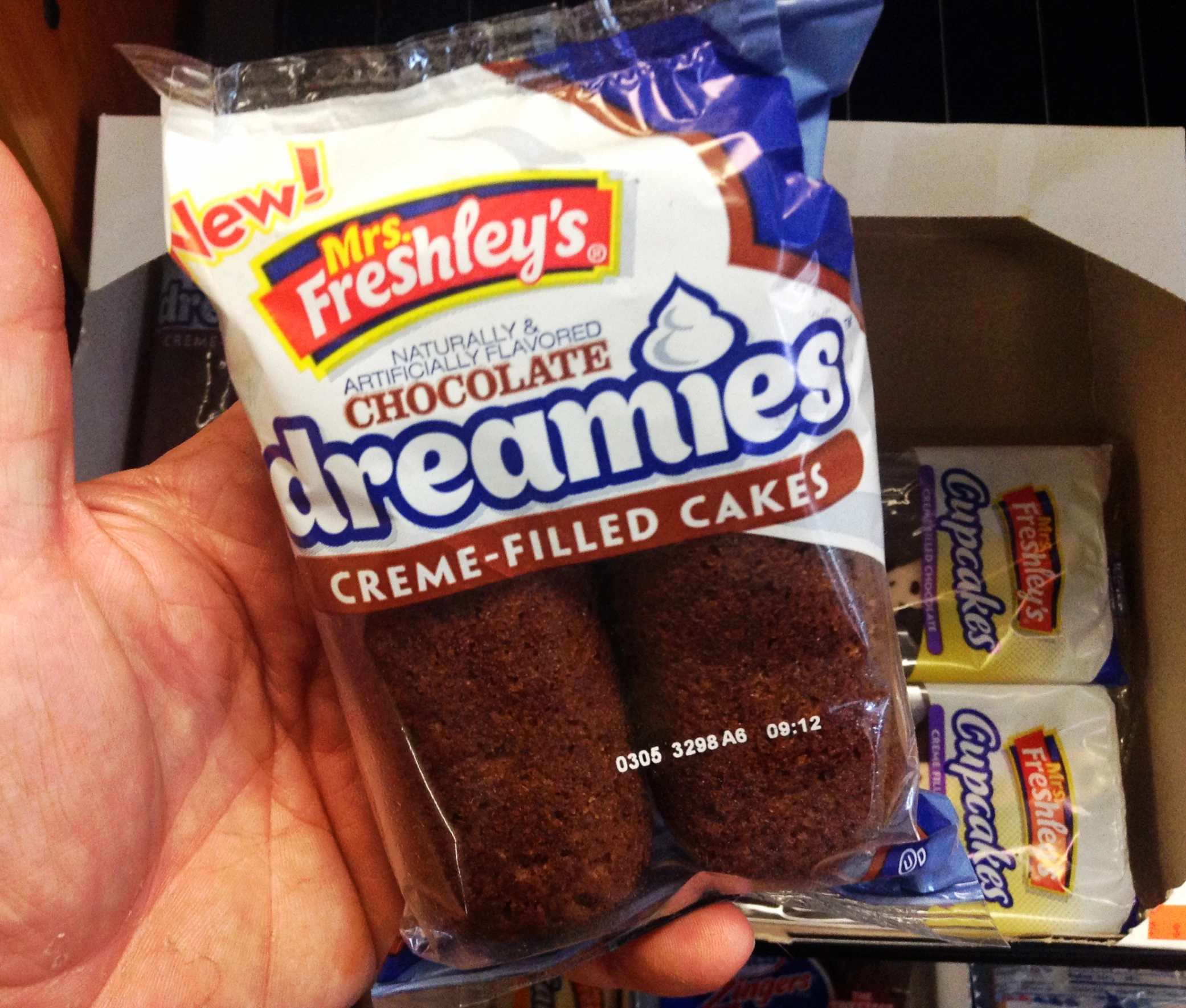 a hand holds a bag of brownie cake mix