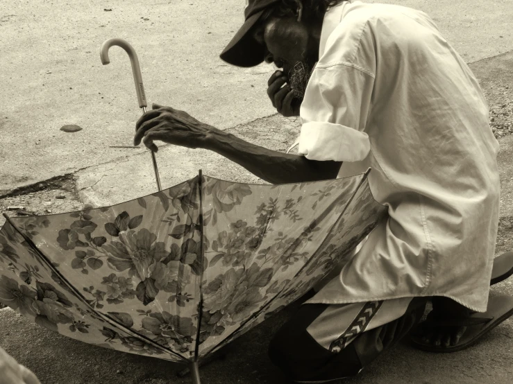 man kneeling down while holding an umbrella
