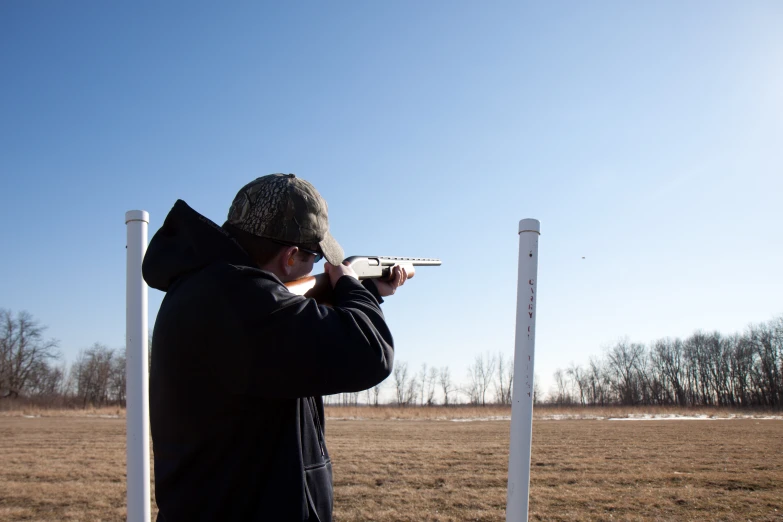 man practicing with gun at open grassy area