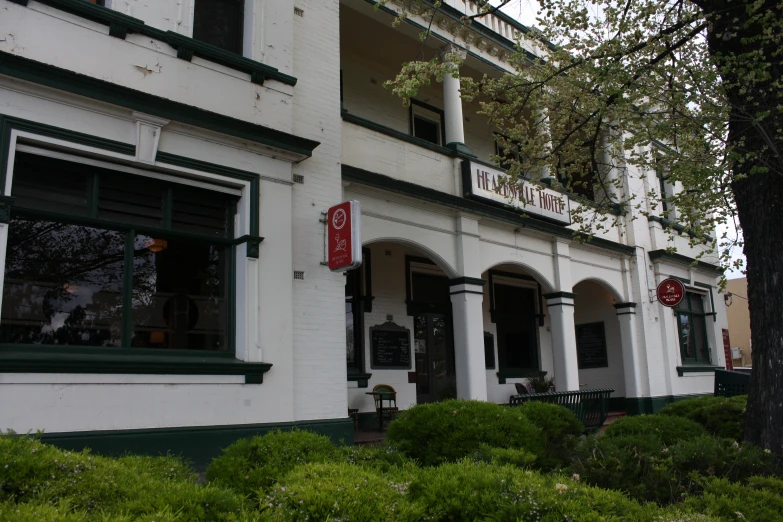 a white brick building has green shutters and green trim