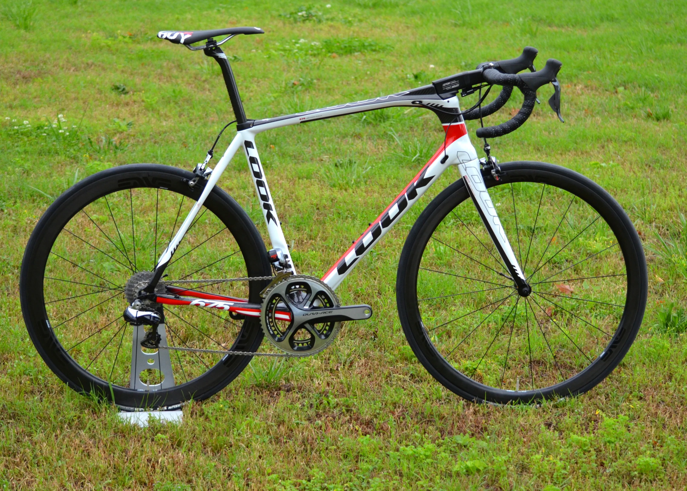 a bicycle parked in the grass next to a green field