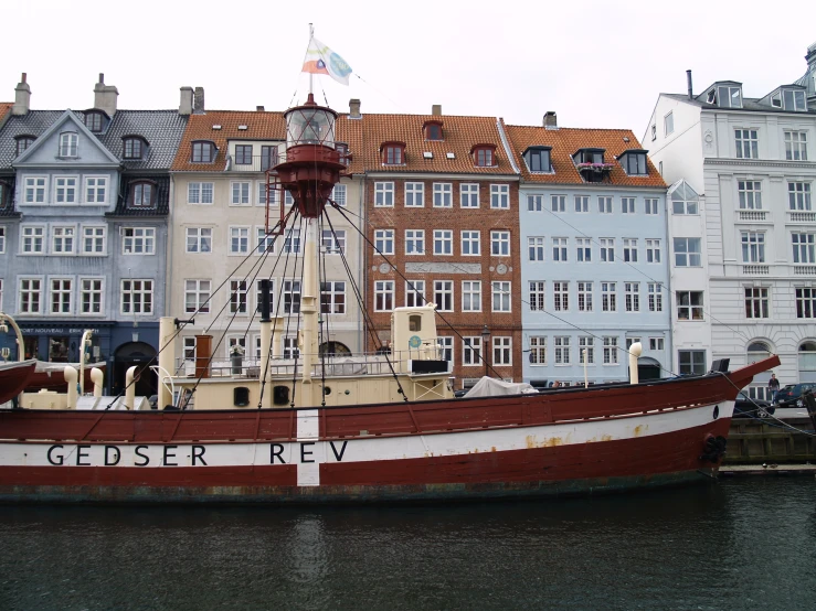 old boats sit in the harbor with lots of buildings on either side of it