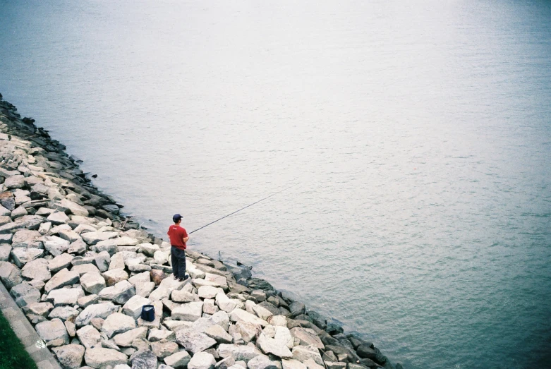 a person stands on the edge of a river while fishing