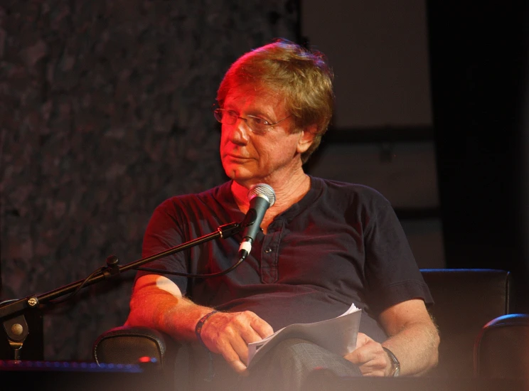 a man is sitting down talking into a microphone