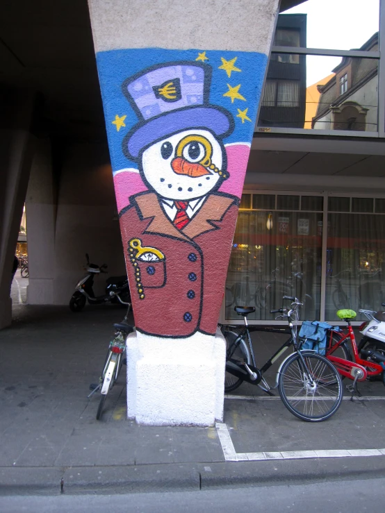 a building with paintings on the side and bikes parked along a street