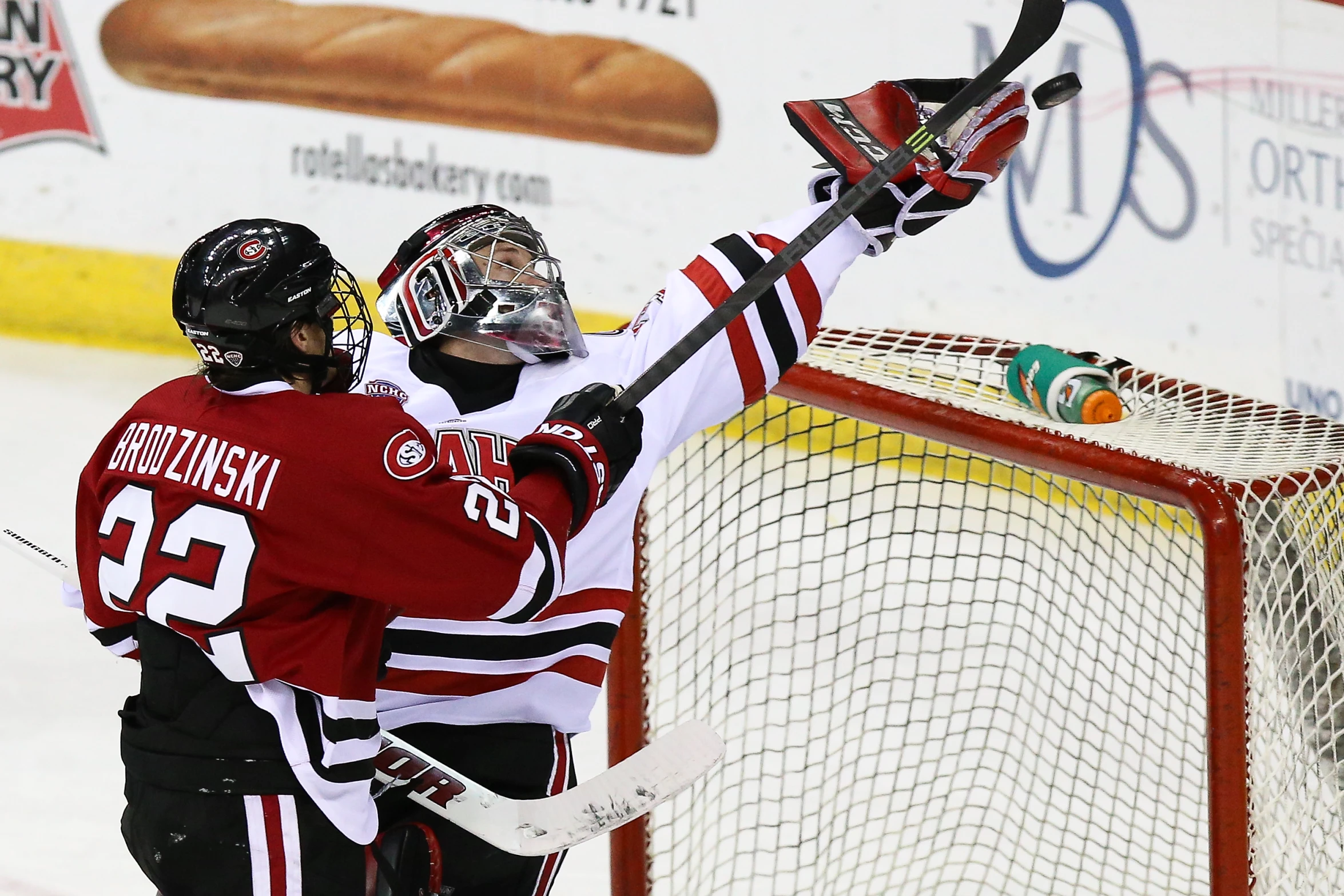 two hockey players are fighting at the net