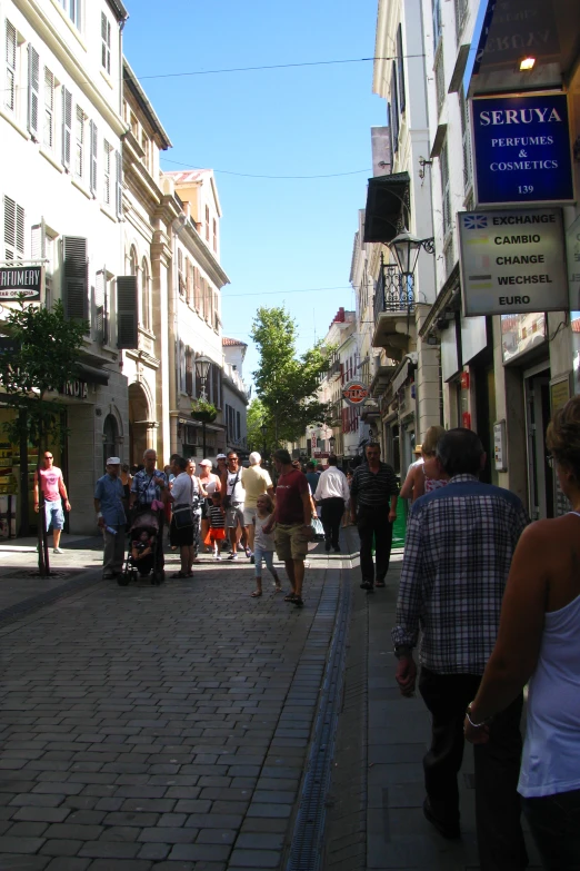 many people are walking down the sidewalk with a scooter