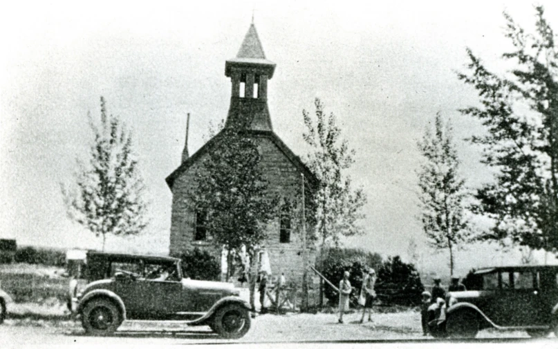 an old po of cars parked in front of a church