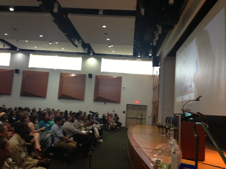 people in chairs looking at a speaker on a stage