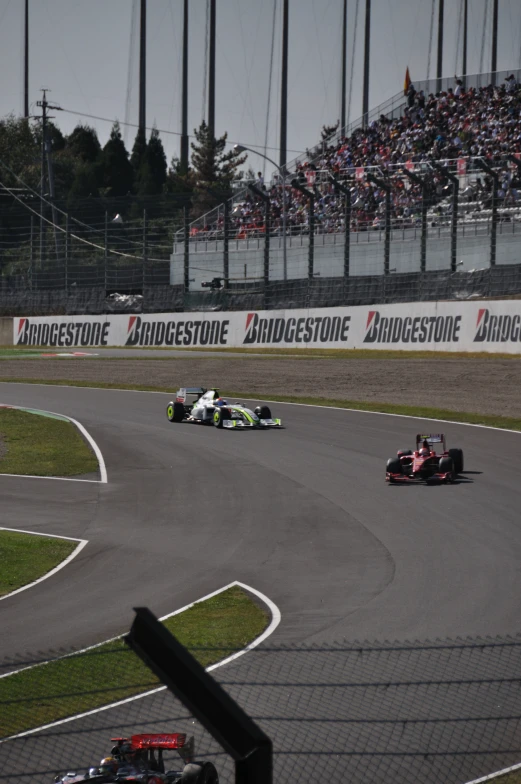 two racing cars going around a corner in front of an audience