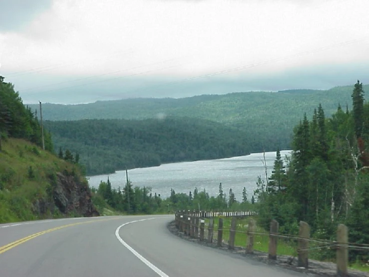 a car driving down a road next to a lake