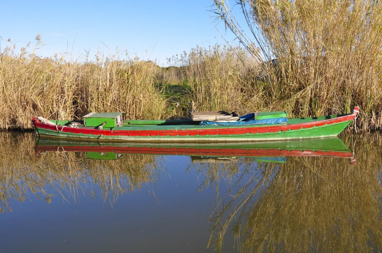 a green red and black row boat on a lake