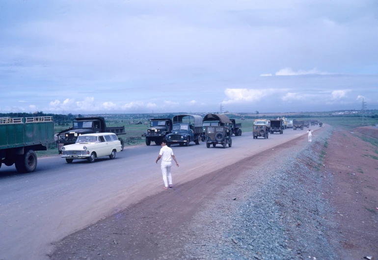 people walking down the road in a line of trucks