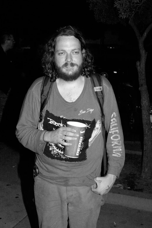 man with beard and long curly hair and beard holding cup in his hand while walking
