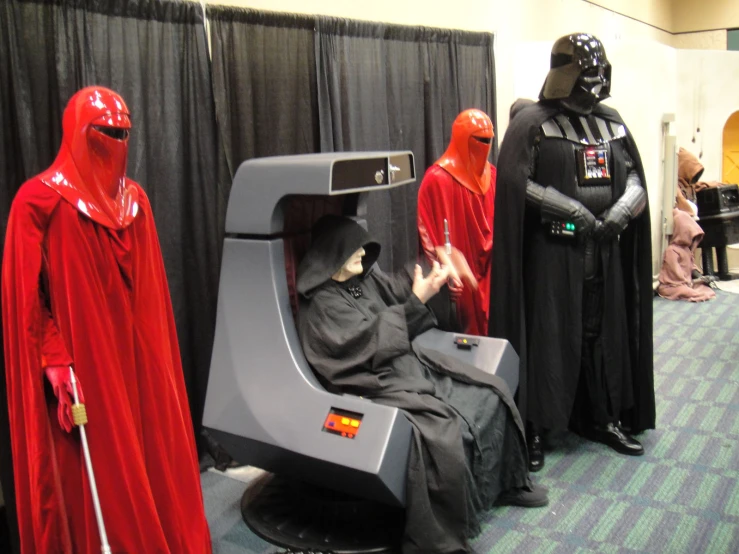 darth vader, sith gry, and droid sit in chairs at the convention