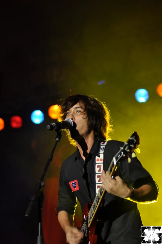 man playing guitar in front of microphone at night