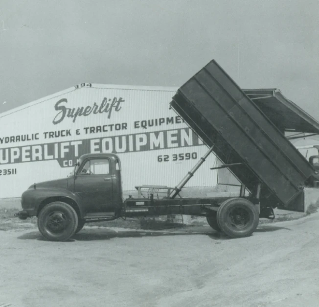 a large black dump truck in front of a shop sign