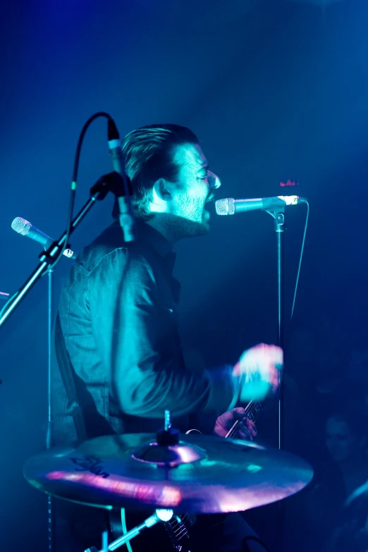 a man playing drums in front of a microphone