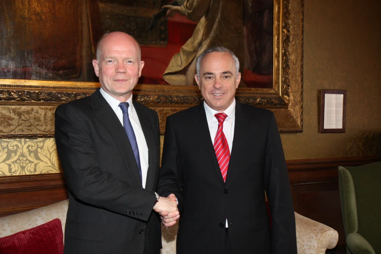 two men are shaking hands in an old style room